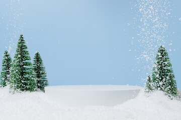 White podium with fir trees and falling snow. Display for winter holidays, New Year and Christmas...