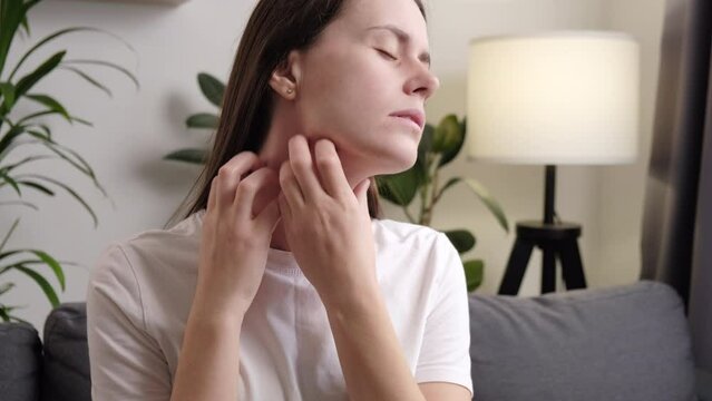 Close up of sad young woman sitting on couch chair scratching neck has dry skin problems dermatitis scabies psoriasis rash itch allergy eczema. Unhealthy food stress lifestyle health care concept