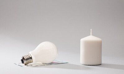 white candle and light bulb on top of 20 euro banknotes, gray background