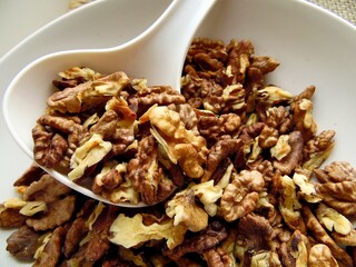 shelled walnut lies on a spoon and on a white dish