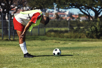 Man, tired and soccer ball on field in training, warmup or workout outdoor in summer. Exercise,...