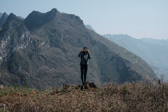 Woman photographing while standing against mountains