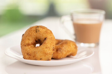 plate of methu vadai with cup of tea on table.