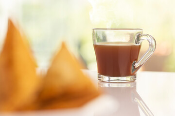 Plate of hot Samosas and cup of tea on table 