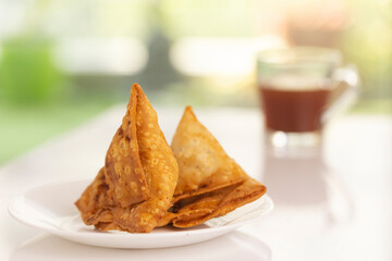 Plate of hot Samosas and cup of tea on table 