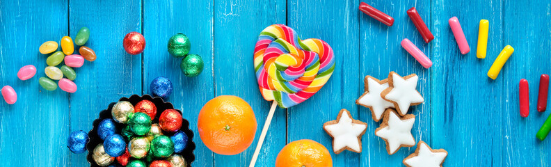 Panoramic banner for Saint Nicholas Day or Nikolaus Tag in German language. Traditional holiday in Germany, Europe. Decorative border - sweets, candy, cookies, satsuma and rainbow lolly pop. Top view
