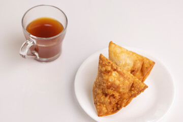 Plate of hot Samosas and cup of tea on table 