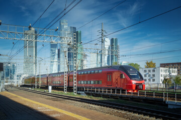 Fototapeta na wymiar City train drive on railroad. Skyscrapers at downtown district on the background. Blue sky in sunny day. Transportation background