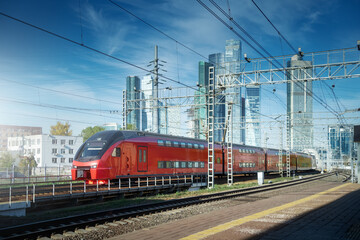 Fototapeta na wymiar City train drive on railroad. Skyscrapers at downtown district on the background. Blue sky in sunny day. Transportation background