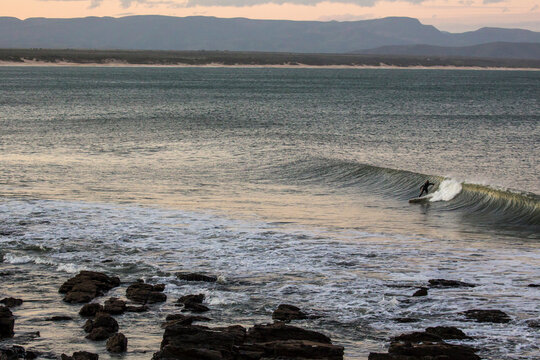 A solo surfer gets his final surf of the day at sunset in Jeffery's Bay, South Africa