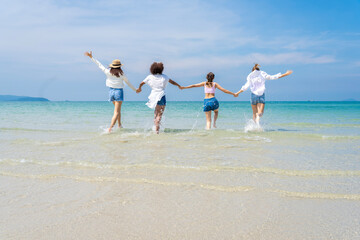 Photo of a group of girls of different ethnicities running and having fun together at the beach. on a fresh day