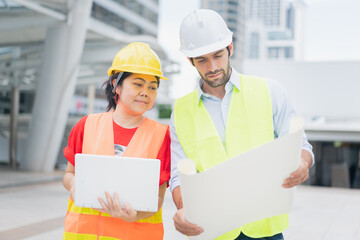 Team of young caucasian man and woman partner explain and inspecting the reconstructed construction holding the blueprint of apartment, at job site, outdoor.