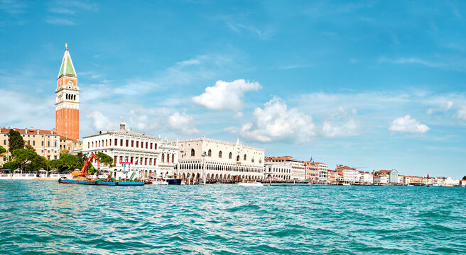 Doge's palace and Campanile on Piazza di San Marco, Venice, Italy. View from the passing ship with water in front. Panoramic banner image with blue sky and feather clouds.