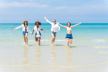 Photo of a group of girls of different ethnicities running and having fun together at the beach. on a fresh day