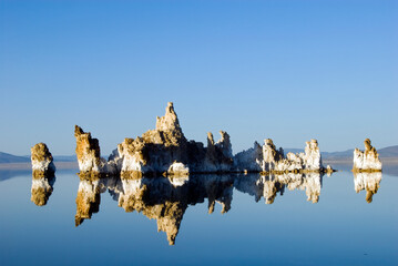 Large tufa formations are illuminated and reflected in afternoon light in Mono Lake, CA.