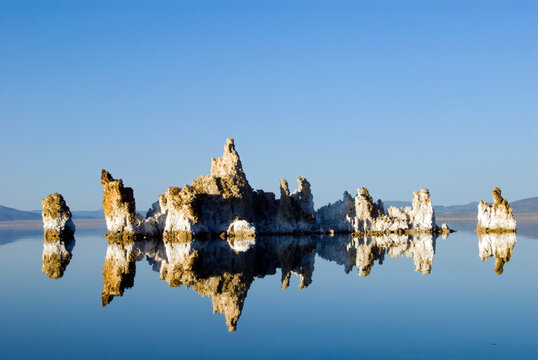 Large tufa formations are illuminated and reflected in afternoon light in Mono Lake, CA.