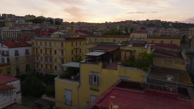 Low flight above old residential buildings in urban borough. Colour houses at twilight. Naples, Italy