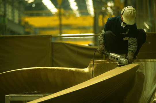 Worker polishing propeller at shipyard in Busan, South Korea.