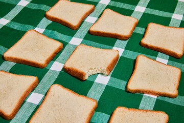 Choice. Original composition with uncooked bread toasts on plaid green and white tablecloth background. Vintage, retro style. Food pop art photography.
