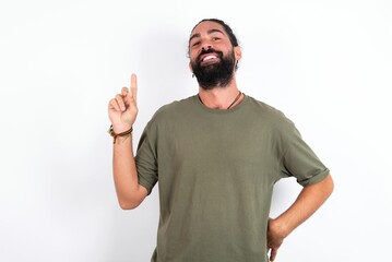 Fototapeta premium young bearded hispanic man wearing green T-shirt over white background holding finger up having idea and posing