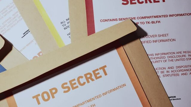 Top shot various types of classified information with color codes and warnings. Red, Orange and Blue for secret, top secret and confidential files and papers. Leaked or exposed sensitive material