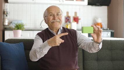 The old man is pointing at the green product in his hand on the sofa, smiling. Creative 3d artists...