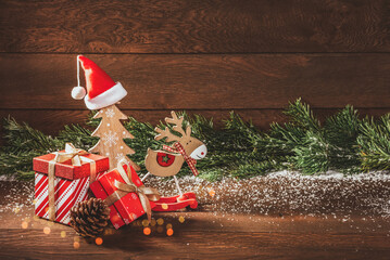 Merry Christmas. Boxes with gifts, wooden Christmas decorations and fir branches on a wooden background