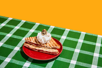 Surreal cake. Perfectionism and colorful minimalism. Meat sandwich, fried toast and raw quail egg on plaid tablecloth background. Food pop art photography.