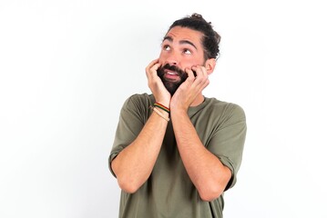 Inspired young bearded hispanic man wearing green t-shirt over white background looking at copyspace having thoughts about future events