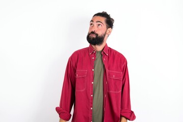 Obraz premium young bearded hispanic man wearing red overshirt over white background making grimace and crazy face, screaming out of control, funny lunatic expressing freedom and wild.