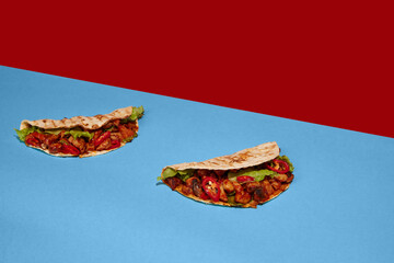 Mexican cuisine. Appetizing and juicy tacos on red-blue background. Vintage, retro style. Food pop...