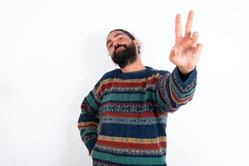 Naklejka premium Caucasian man with beard wearing sweater over white background directs fingers at camera selects someone. I recommend you. Best choice