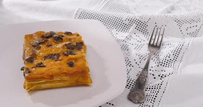 Fetta di lasagna al forno con funghi e zucca nel piatto