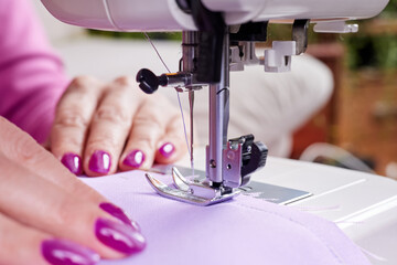 Woman sewing a dress on a sewing machine. Close-up, selective focus