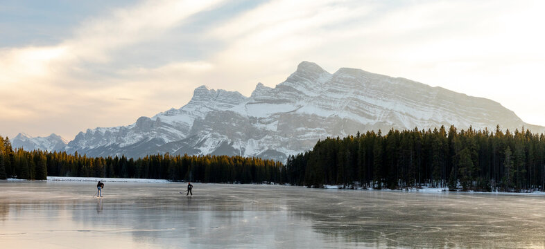 People ice skating on frozen Two Jack Lake, Alberta, Canada - Powered by Adobe