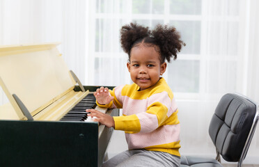 A beautiful little girl is playing the piano in the living room at home.