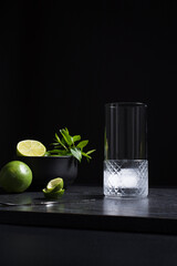 Un vaso con hielo vacío para echar zumo de lima  sobre fondo negro