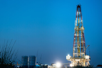 Oil field drilling rig derrick structure on dusk sky background. Industrial and business operation...