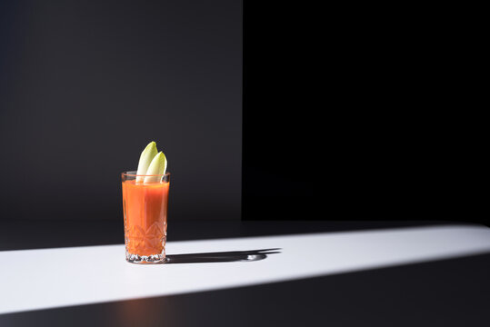 Vaso de jugo de zanahoria con hojas de endibia sobre fondo oscuro	