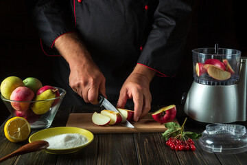 The chef prepares fruit jam from fresh apples. The cook cuts apples for chopping in a blender. Menu or recipe idea for hotel or restaurant