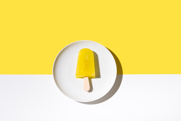 Paleta de hielo sabor limón. Palo de helado sobre fondo amarillo y blanco. Concepto de verano....