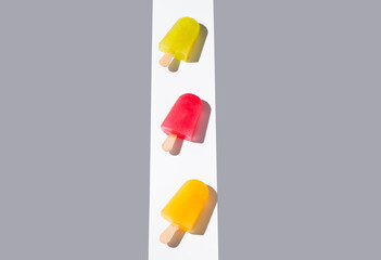 Paletas de hielo de colores. Palitos de helado naranja, rojo y amarillo sobre fondo gris. Concepto...
