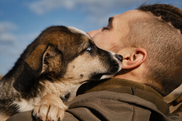Man chose puppy from shelter. Young Caucasian man with dreadlocks hugs blue-eyed Alaskan husky...