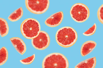 Fototapeta na wymiar Grapefruit slices on bright blue background falling levitating in the air. Isolated citrus fruits set. Vitamin C food concept