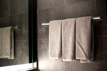 towel on grey cement wall with grey towel in bathroom