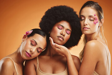 Beauty, diversity and skincare with a model woman friends in studio on an orange background for wellness. Health, skin and cosmetics with a female group posing to promote a product or treatment