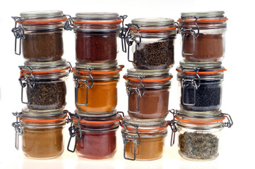 Bocaux d'épices et d'herbes aromatiques empilés en gros plan sur fond blanc