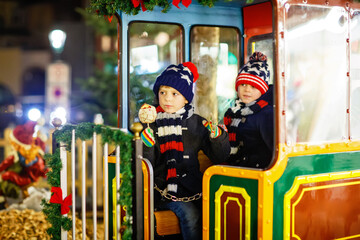 Two little kids boys on carousel at Christmas market