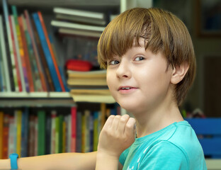Schoolboy is smile and looking camera near a bookshelves
