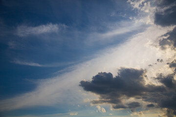 Naklejka na ściany i meble Clouds that portend rain creep into the blue sky.